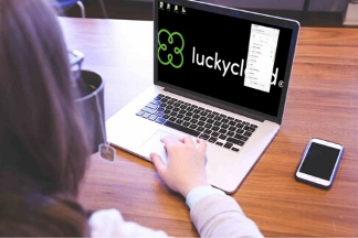 Vogelperspektive ueber die Schultern einer Frau. Auf dem Bildschirm eines Laptops ist das luckycloud-Logo zu sehen.