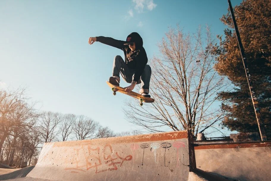 A man jumps with a skateboard in front of a blue sky.